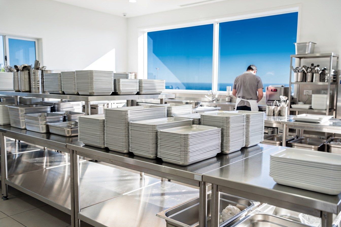 A commercial catering kitchen set up and ready, seen from behind the stainless steel benches, before an event.